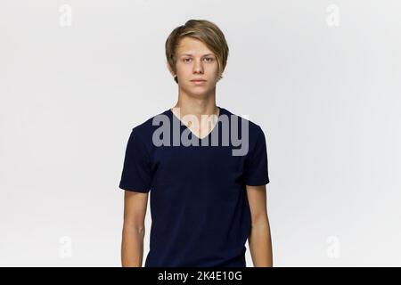 Schöne glückliche junge Mann mit blauen t-shirt Studio Portrait gegen weiße Wand Stockfoto