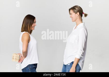 Überrascht junge Frau erhält ein Geschenk von ihrem Freund. Glücklich und lächelnd weibliche Freunde Stockfoto