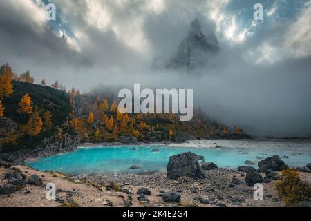 Fantastisches Wander-, Foto- und Reiseziel. Malerischer See Sorapis mit bunten Lärchen und nebligen Bergen. Wunderschöne Herbstlandschaft in Stockfoto