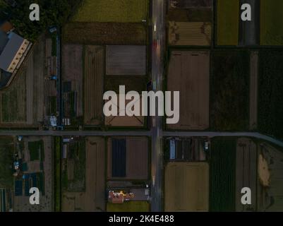 Draufsicht auf die Straße durch Felder in ruhiger Nachbarschaft bei Dämmerung Stockfoto