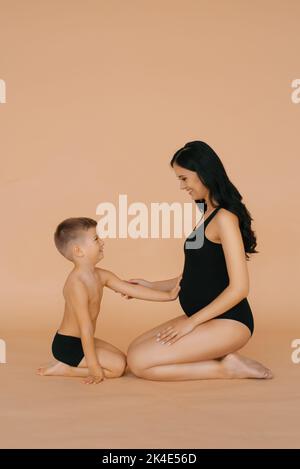 Das kleine Kind hält seine Hände auf den Bauch seiner Schwangeren Stockfoto
