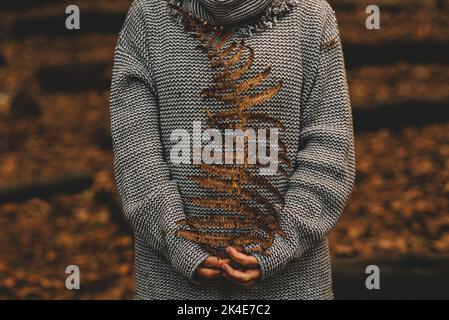 Herbst und Umwelt Menschen Lifestyle-Konzept mit unkenntlichen Frau hält trockene Blatt gegen einen Blätter braunen Hintergrund im Wald. Bild Stockfoto