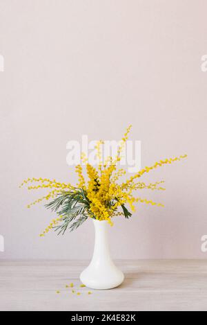 Bouquet von gelben Mimosenblüten steht in einer weißen Keramikvase. Das Konzept des 8. März, Ostern, glücklicher Frauentag Stockfoto