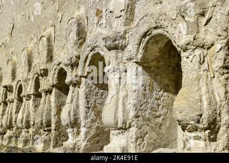 Steinreliefsäulen in die Wand geschnitzt. Struktur aus altem verfallenen Mauerwerk. Alte halb zerstörte Synagoge. Rashkov, Moldawien. Selektiver Fokus. Stockfoto