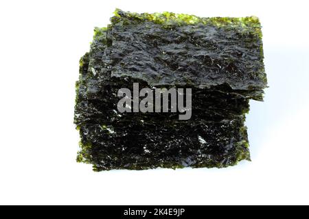 Gewürzter Seetang-Snack. Algenblätter in einem Stapel auf weißem Hintergrund gestapelt. Stockfoto