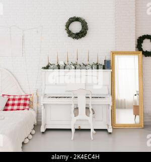 Weißes Klavier zu Weihnachten und Neujahr im Wohnzimmer des Hauses dekoriert Stockfoto