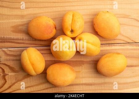 Mehrere Bio-gelbe Ananas-Aprikosen, Nahaufnahme, auf einem weißen Holztisch, Draufsicht. Stockfoto