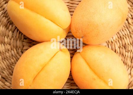 Mehrere Bio-gelbe Ananas-Aprikosen, Makro, auf einer Strohmatte, Draufsicht. Stockfoto