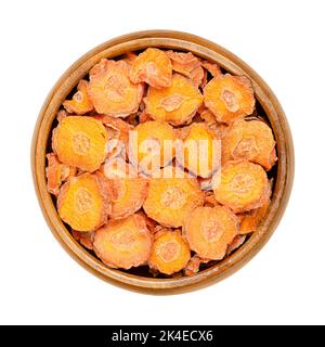 Dehydrierte Karottenscheiben in einer Holzschüssel. Trockene Scheiben von Daucus carota, einem Wurzelgemüse mit oranger Farbe. Essbare Taproot-Stücke. Nahaufnahme von oben. Stockfoto