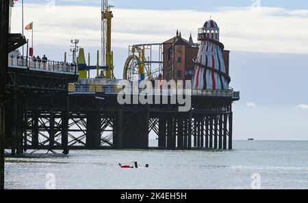 Brighton UK 2. October 2022 - Ein Schwimmer am Brighton Palace Pier nach heftigen Regenschauern früher, aber sonnigeren Bedingungen werden für den Rest des Tages prognostiziert. : Credit Simon Dack / Alamy Live News Stockfoto