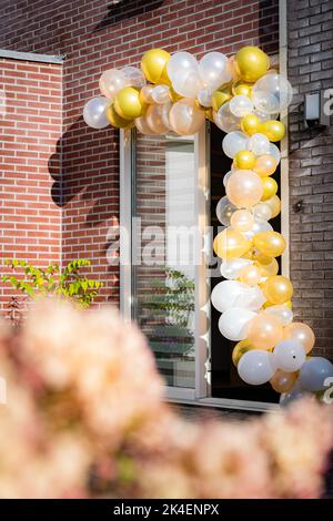 Hochzeitsdekorationen an der Tür eines mit Bändern und Luftballons verzierten Dorfhauses Stockfoto