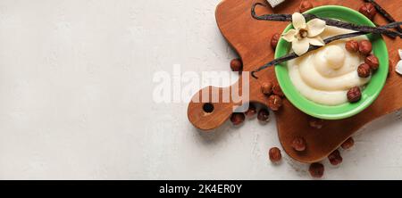 Schüssel mit köstlichem Vanillepudding und Haselnüssen auf weißem Hintergrund mit Platz für Text Stockfoto