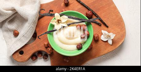 Schüssel mit köstlichem Vanillepudding und Haselnüssen auf weißem Hintergrund Stockfoto