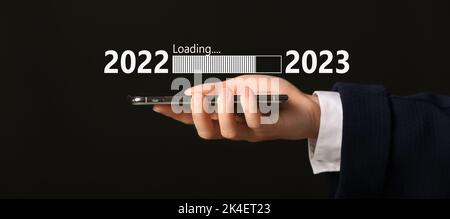 Geschäftsfrau mit Mobiltelefon auf dunklem Hintergrund. Konzept des neuen Jahres 2022 Stockfoto