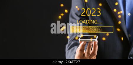 Geschäftsmann mit Mobiltelefon auf dunklem Hintergrund. Konzept des neuen Jahres 2022 Stockfoto