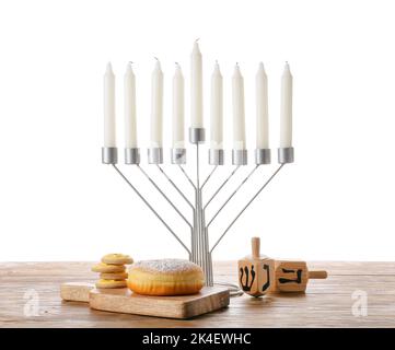 Menorah mit Kerzen, Dreidels, Donut und Keksen für die Chanukka-Feier auf einem Holztisch vor weißem Hintergrund Stockfoto