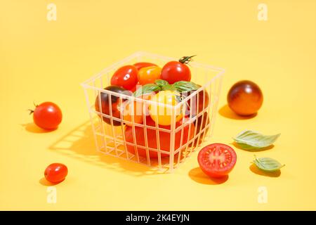 Korb mit frischen reifen Tomaten auf farbigem Hintergrund Stockfoto