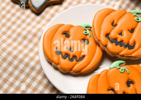 Teller mit Halloween Kürbiskeksen auf karierter Serviette, Nahaufnahme Stockfoto