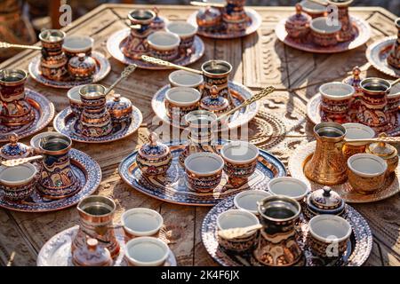 Viele goldene Kupferkessel und kleine Tassen, die für die Zubereitung von türkischem Kaffee verwendet werden. Stockfoto