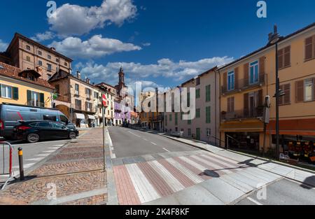 Fossano, Piemont, Italien - 09. September 2022: Via Marconi mit den alten bunten Häusern und dem Glockenturm der Kirche der SS Trinita in der dist Stockfoto