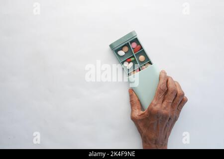 Ältere Frauen, die eine Schachtel mit medizinischen Pillen auf weißem Hintergrund halten Stockfoto