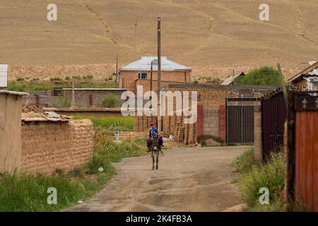 Kleiner Junge auf einem Esel in einem abgelegenen Dorf auf dem Weg zum Song Kul See Stockfoto