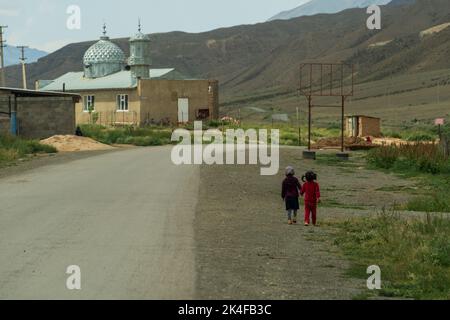 Zwei kleine Mädchen vor der Moschee in einem abgelegenen Dorf auf dem Weg zum Song Kul See Stockfoto