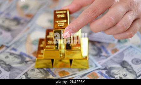 Frau Hand legt goldenen Barren der Dollar-Banknote Stockfoto