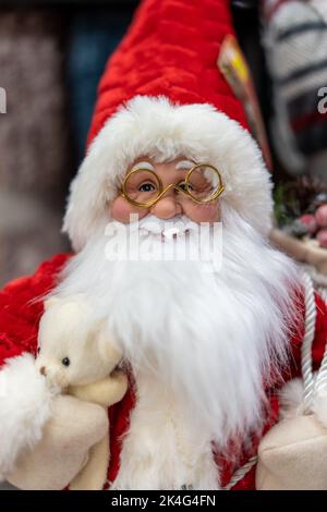 Klassisches Weihnachtsmann-Ornament mit goldgerillten Gläsern, die einen Teddybären kuscheln Stockfoto