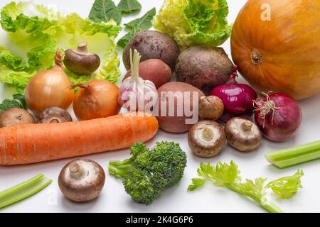 Karotten, Pilze, Kürbis, Kohlblätter, Kartoffelknollen und Brokkoli auf Weiß. Draufsicht Stockfoto