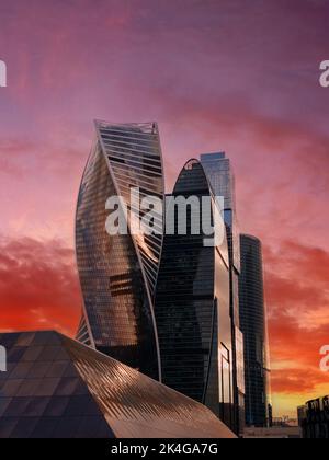 Die Gipfel der modernen Unternehmensgebäude vor dem düsteren roten Sonnenuntergangshimmel. Hochhäuser und Wolkenkratzer Moscow International Business Center. Stockfoto