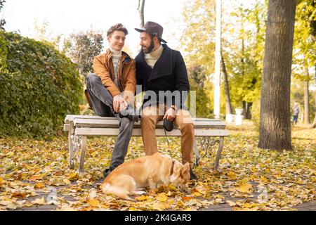 Vater und Sohn mit einem Haustier auf einem Spaziergang im Herbstpark. Stockfoto