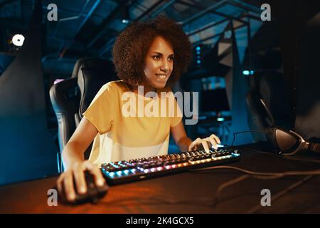 Junge lockige Frau, die Cyber-Spiele spielt. Stockfoto