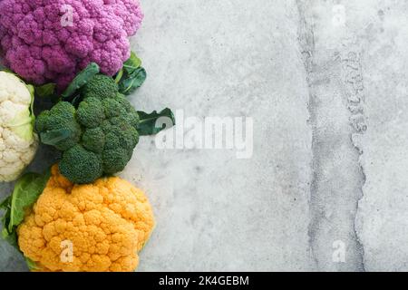 Colorfu-Blumenkohl. Verschiedene Arten von Blumenkohl auf grauem Beton Hintergrund. Violette, gelbe, weiße und grüne Farbkabbage. Brokkoli und Romanesco. Stockfoto