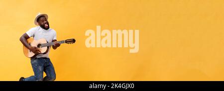 In voller Länge Foto von Angeregten künstlerische Mann, der seine Gitarre spielen. Auf gelben Hintergrund. Stockfoto