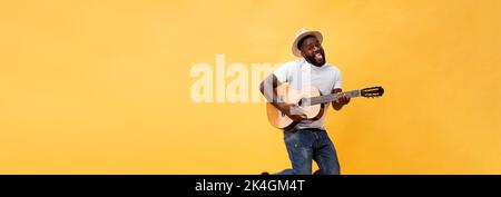 In voller Länge Foto von Angeregten künstlerische Mann, der seine Gitarre spielen. Auf gelben Hintergrund. Stockfoto