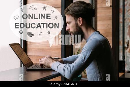 Online-Schulungen. Fernunterricht. Virtuelle Studie. Webinar-Kurs. Smart Hipster Kerl Student beobachten Video-Lektion auf Laptop in Loft-Innencafe wi Stockfoto