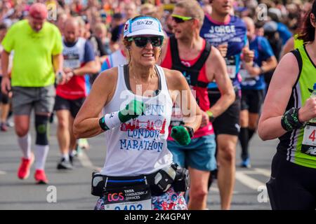 London, 2.. Oktober 2022. Mehr als 40.000 Teilnehmer gehen zum London Marathon 42. auf die Straßen der Hauptstadt. Die Veranstaltung, die Eliteläufer und Rollstuhlfahrer anzieht, bringt auch Millionen Pfund für wohltätige Zwecke durch die Teilnahme von Club- und Fitnessläufern zusammen mit denen, die nur die 26 Meilen Herausforderung annehmen wollen. Eine reife Läuferin auf der Strecke des London Marathon. Stockfoto