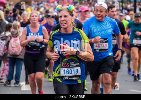 London, 2.. Oktober 2022. Mehr als 40.000 Teilnehmer gehen zum London Marathon 42. auf die Straßen der Hauptstadt. Die Veranstaltung, die Eliteläufer und Rollstuhlfahrer anzieht, bringt auch Millionen Pfund für wohltätige Zwecke durch die Teilnahme von Club- und Fitnessläufern zusammen mit denen, die nur die 26 Meilen Herausforderung annehmen wollen. Eine reife Läuferin auf der Strecke des London Marathon. Stockfoto