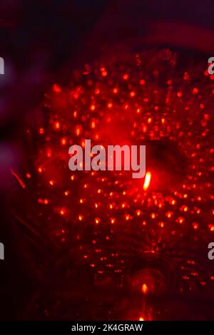 Regnerische Nacht in der großen Stadt, das Auto auf der Autobahn und leuchtet ein blendes Licht. Nahaufnahme von der Ebene der Trennlinie Stockfoto