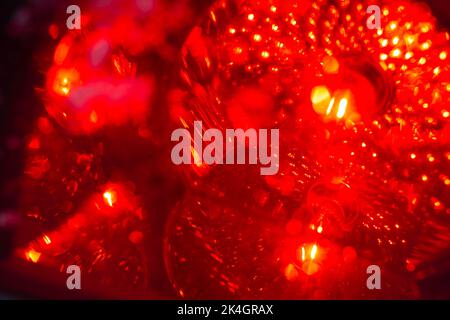 Regnerische Nacht in der großen Stadt, das Auto auf der Autobahn und leuchtet ein blendes Licht. Nahaufnahme von der Ebene der Trennlinie Stockfoto