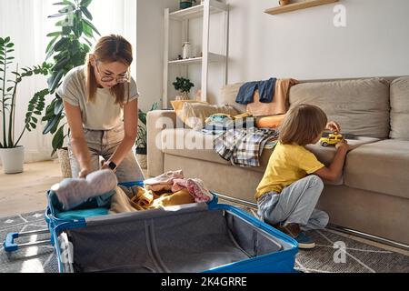 Mutter und Kind packen Dinge zusammen in einen Koffer. Familienumzug, Flucht aus dem Land, geschlossene Grenzen Stockfoto