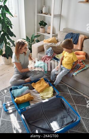 Mutter und Kind packen Dinge zusammen in einen Koffer. Familienumzug, Flucht aus dem Land, geschlossene Grenzen Stockfoto