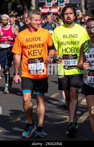 Blinder Läufer mit Führungsläufer, beim TCS London Marathon 2022, auf der Tower Hill Road, City of London, Großbritannien. Hoby Allen und Kevin Drodge Stockfoto