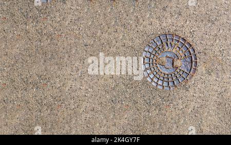 Abdeckung der Wasserventilplatte für kleine runde Lochkappe in der Mitte von grauem Asphalt Stockfoto