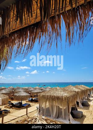 Eine vertikale Aufnahme von Liegestühlen und Strohschirmen auf einer wundervollen tropischen Insel im Luxusresort Stockfoto
