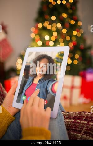 Rothaarige Frau sitzt auf der Couch mit Tablet an Weihnachten zu Hause im Wohnzimmer Stockfoto