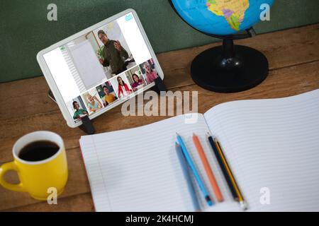 Lächelnd verschiedene Grundschüler mit Lehrer während der Klasse auf Tablet-Bildschirm. Kommunikationstechnik und Online-Bildung, digital Composite Stockfoto