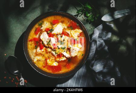 Wärmende Herbstsuppe mit roten Linsen, Hühnerfilet, Gemüse, Gewürzen und Paprika, Gemüsefutter. Grüner Tisch, hartes Licht mit Blattschatten, oben Vie Stockfoto