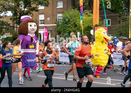 London, Großbritannien. 02. Oktober 2022. Einige Läufer sehen sich in ausgefallenen Kostümen an, als sie während des Londoner Marathons über die 21 km laufen. Zum ersten Mal wurde eine Strecke der London Marathon-Route in Rainbow Row umgewandelt, um die LGBTQIA-Community zu feiern, die Inklusivität zu fördern und eine Partyatmosphäre zu schaffen, die auf der Meile 21 aufgeht. Marathonläufer passieren zwei Etappen mit Musik- und Drag-Darbietungen und die Straße, die in der Regel Butcher Row in Limehouse heißt, ist mit bunten Flaggen und Adern bedeckt. Kredit: SOPA Images Limited/Alamy Live Nachrichten Stockfoto